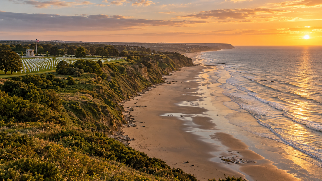 Golden hour view of Omaha Beach in Normandy with the American Cemetery visible on the bluff above.